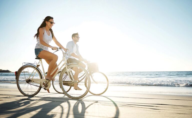man and woman riding on bikes along the beach